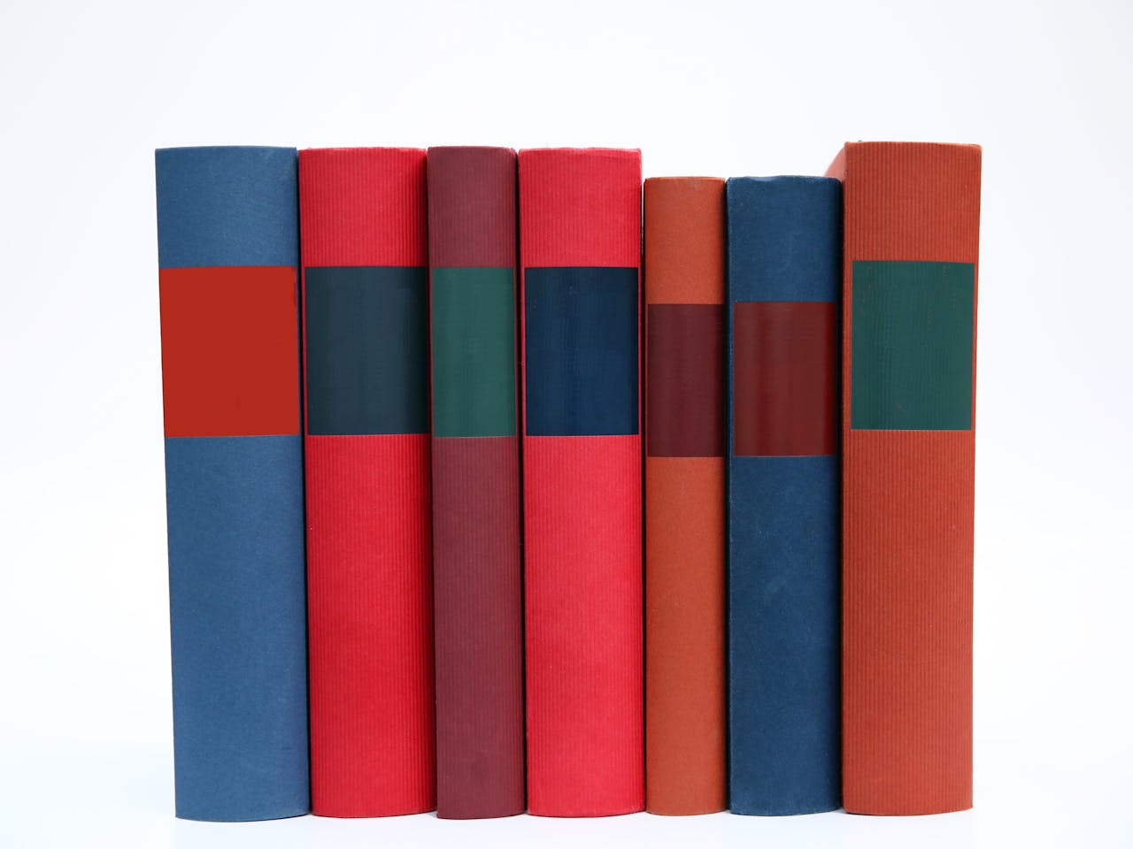 A row of colorful books with plain spines arranged on a white surface.